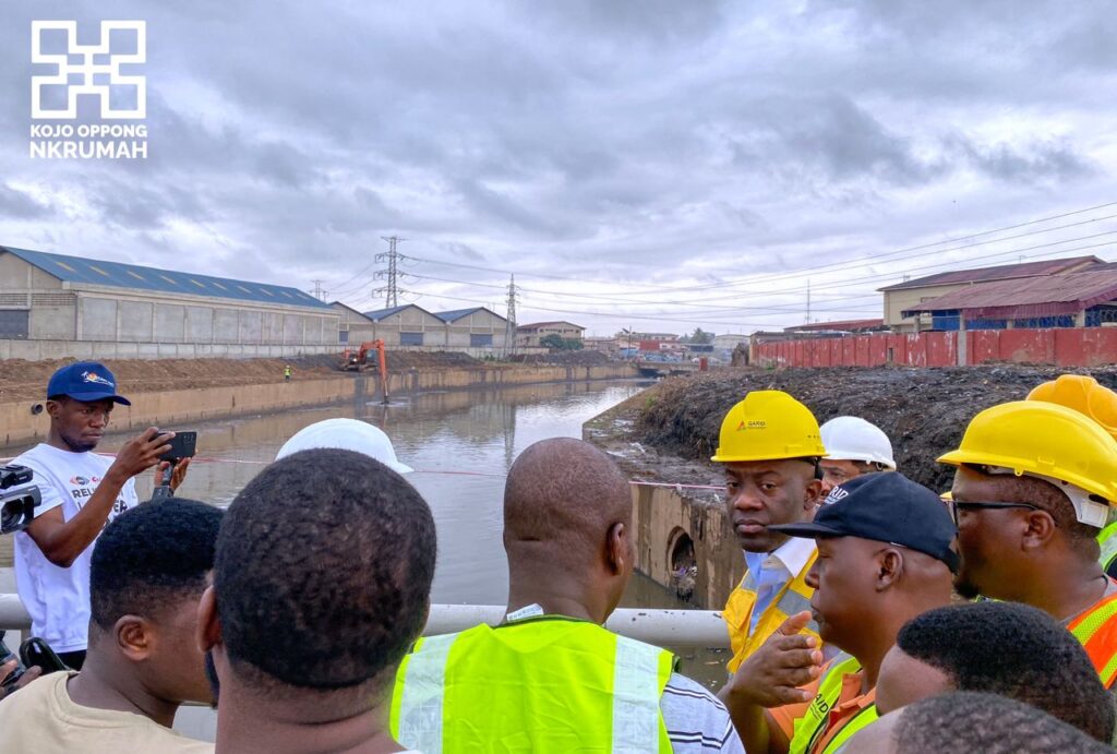 Kojo Oppong Nkrumah, minister of works and housing (in yellow vest) interacting with officials during an inspection of ongoing dredging works on the Odaw River Basin.